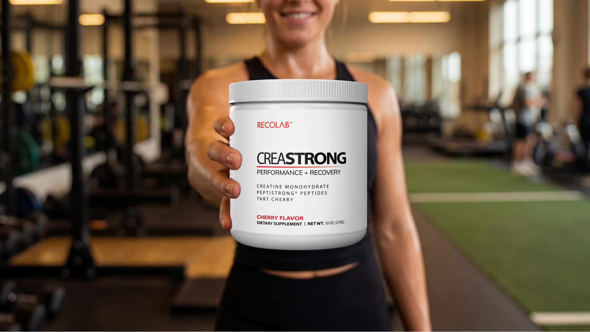 Woman holding a container of Reclast Creastrong supplement in a gym setting
